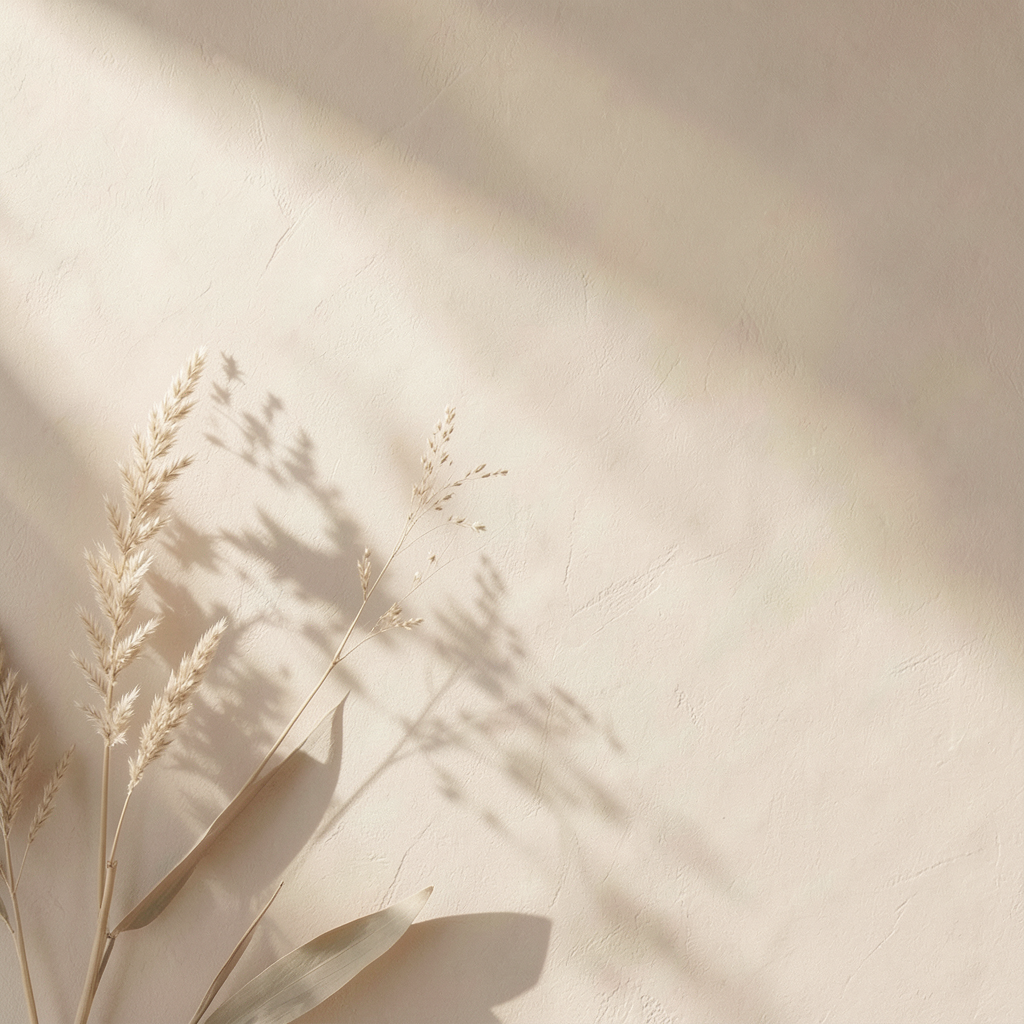 Ästhetischer Hintergrund mit getrocknetem Gras und Gräser-Schatten auf einer cremefarbenen Wand, ideal für Naturkosmetik-Präsentationen.