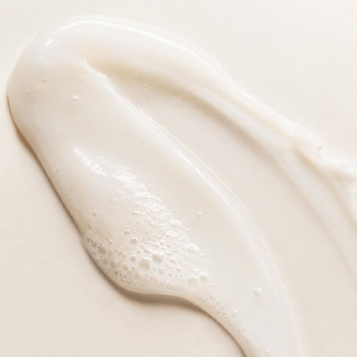 Careskin Reinigung Textur Nahaufnahme – cremige Reinigungsmilch-Textur mit Schaum auf beigem Hintergrund