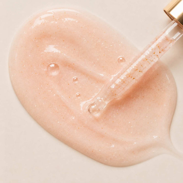 Careskin Serum Textur Nahaufnahme mit Pipette – rosafarbene Serum-Textur mit goldenen Partikeln auf beigem Hintergrund